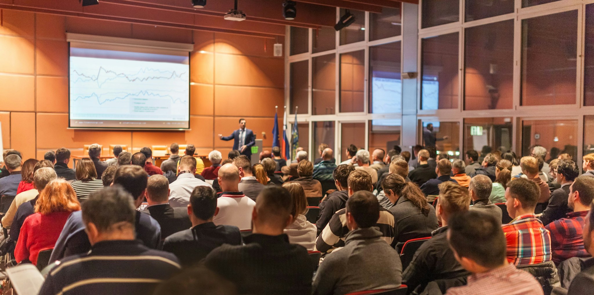 Attendees at a professional conference watch a speaker presentation