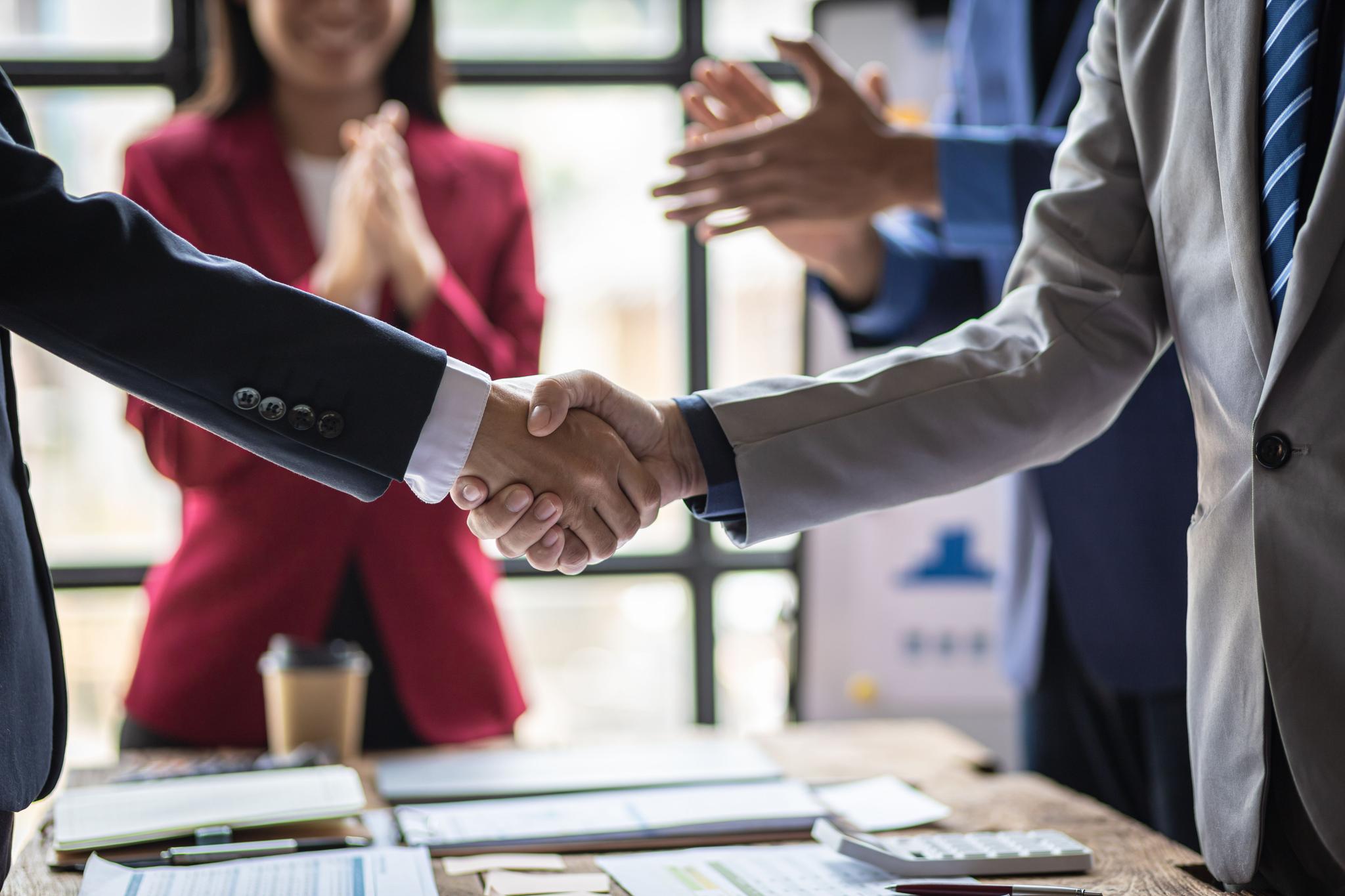 Two men shake hands at a business partner meeting